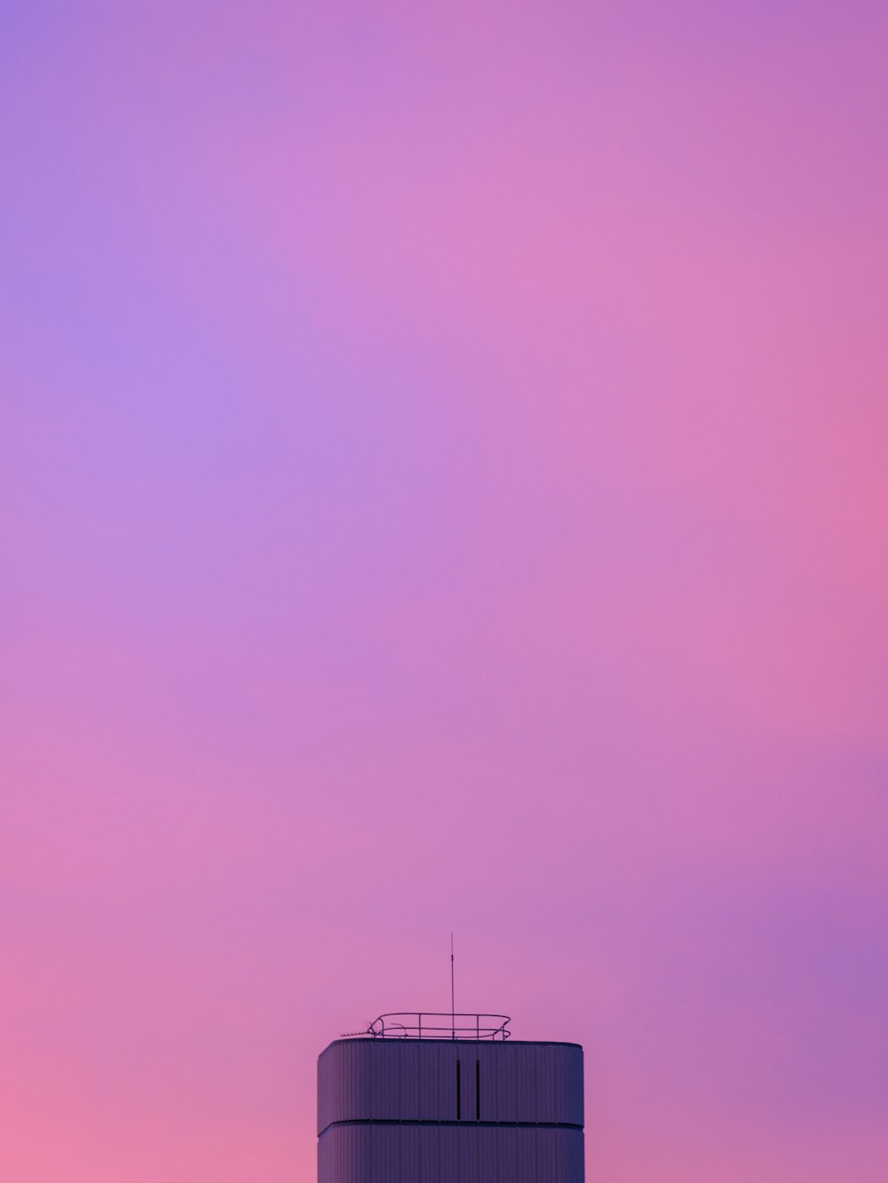 a water tower with a pink sky in the background