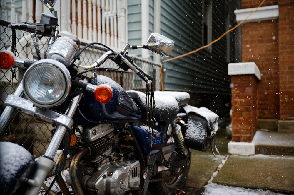 a motorcycle parked in front of a house covered in snow