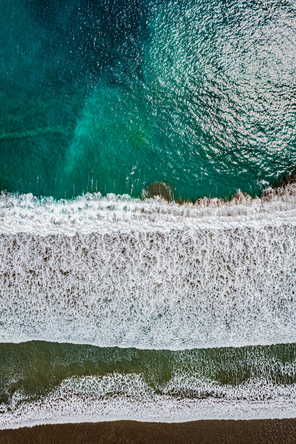 an aerial view of a beach with waves crashing on the shore