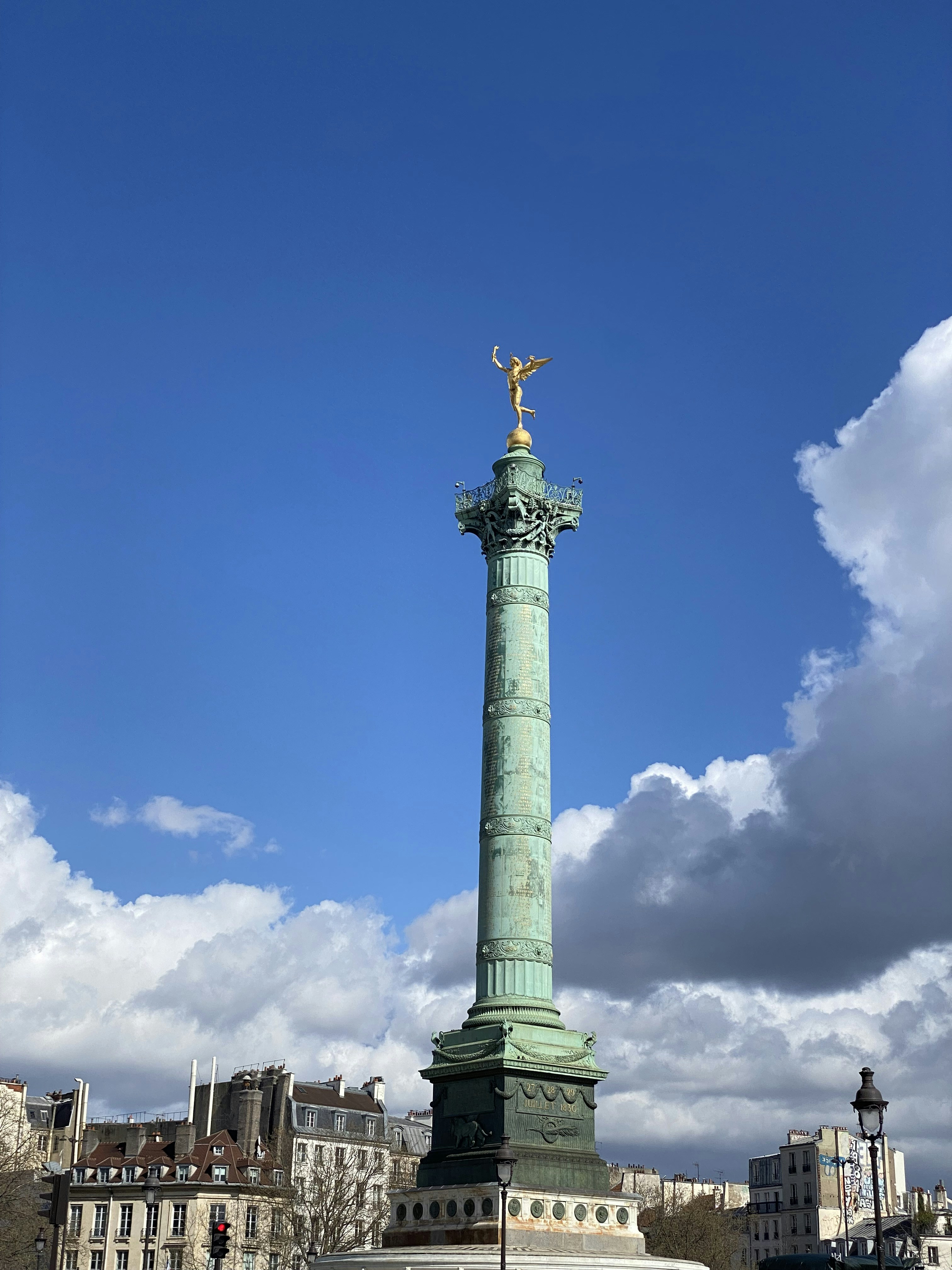 a tall green monument with a gold statue on top of it