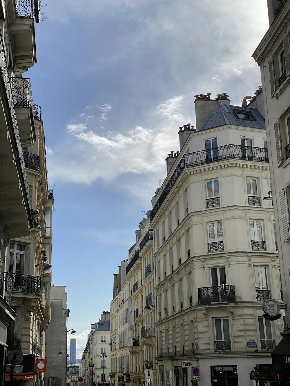 a city street lined with tall buildings under a cloudy blue sky