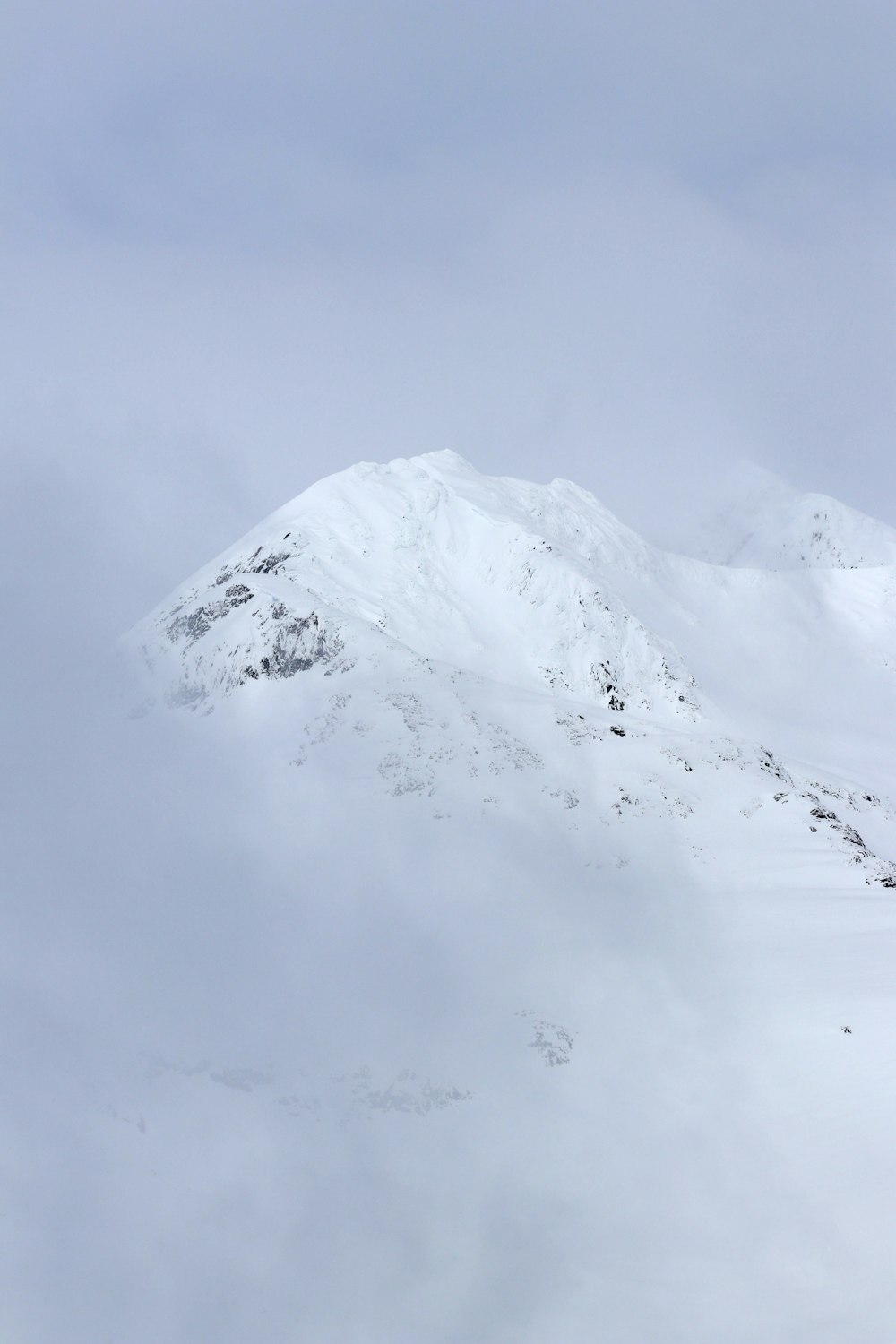 a snow covered mountain with a person on skis