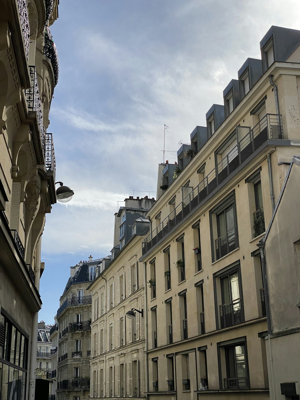 a city street lined with tall buildings under a cloudy blue sky