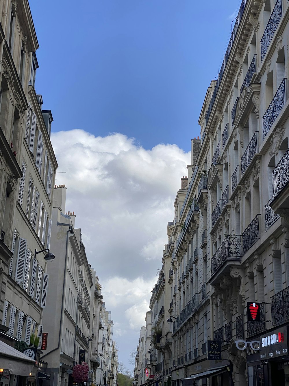 Une rue de la ville bordée de grands immeubles sous un ciel bleu nuageux