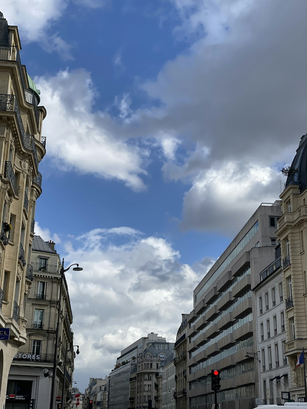 a city street filled with tall buildings under a cloudy blue sky