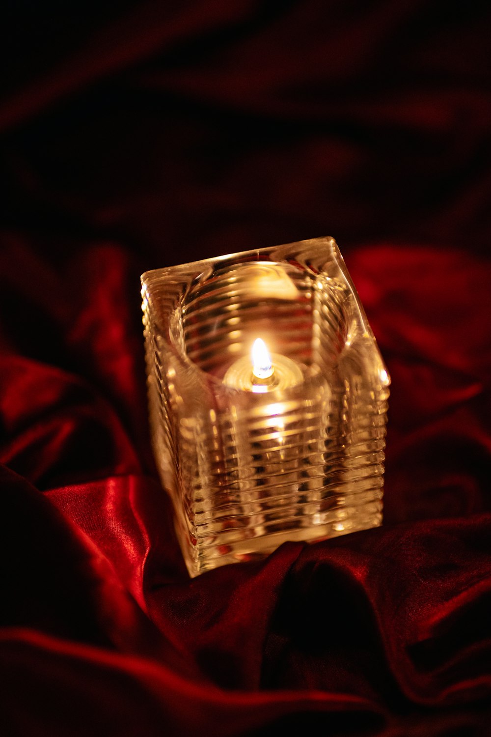 a lit candle sitting on a red cloth