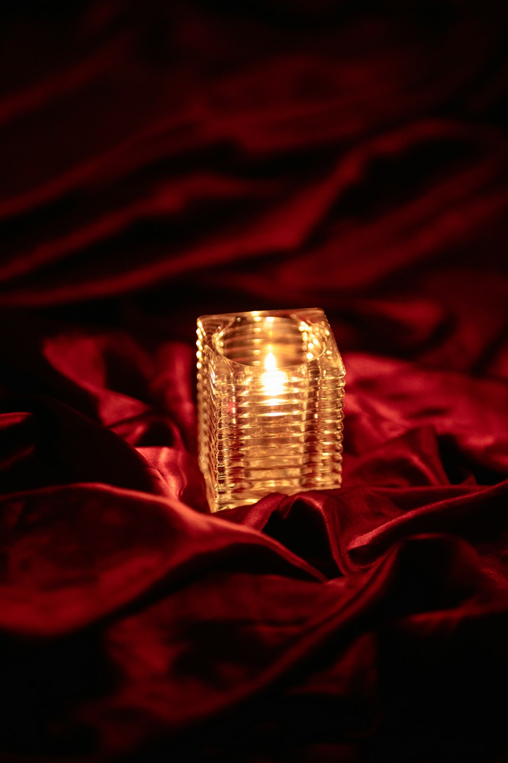 a lit candle sitting on a red cloth