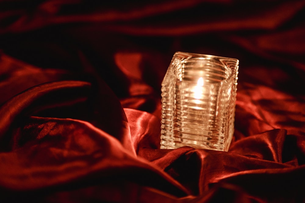 a small glass candle sitting on a red cloth
