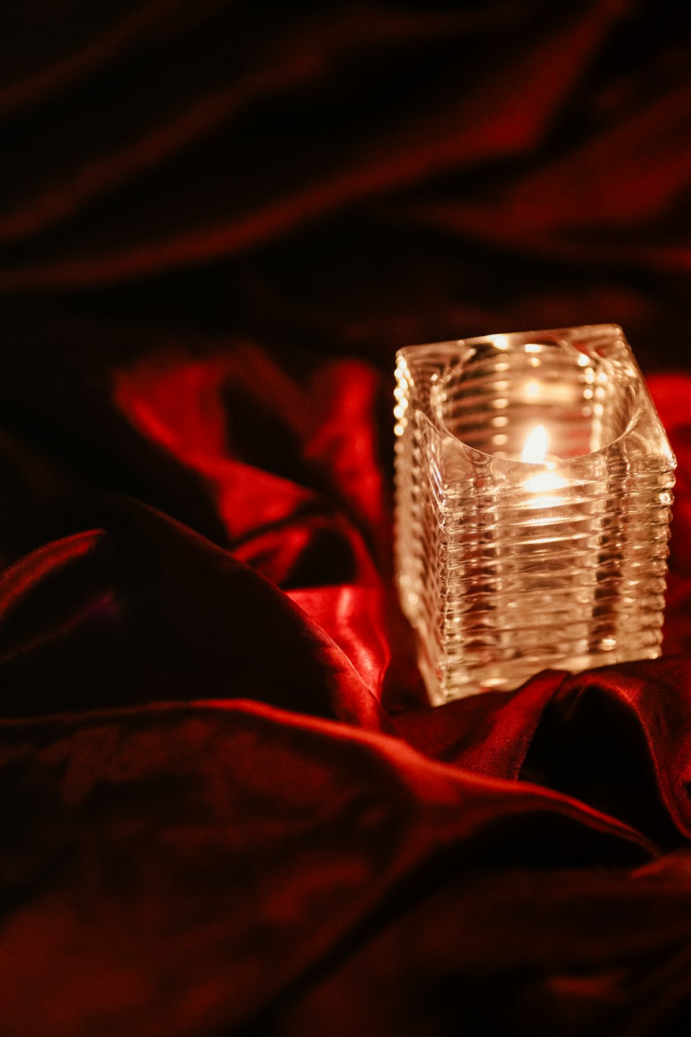 a lit candle sitting on a red cloth
