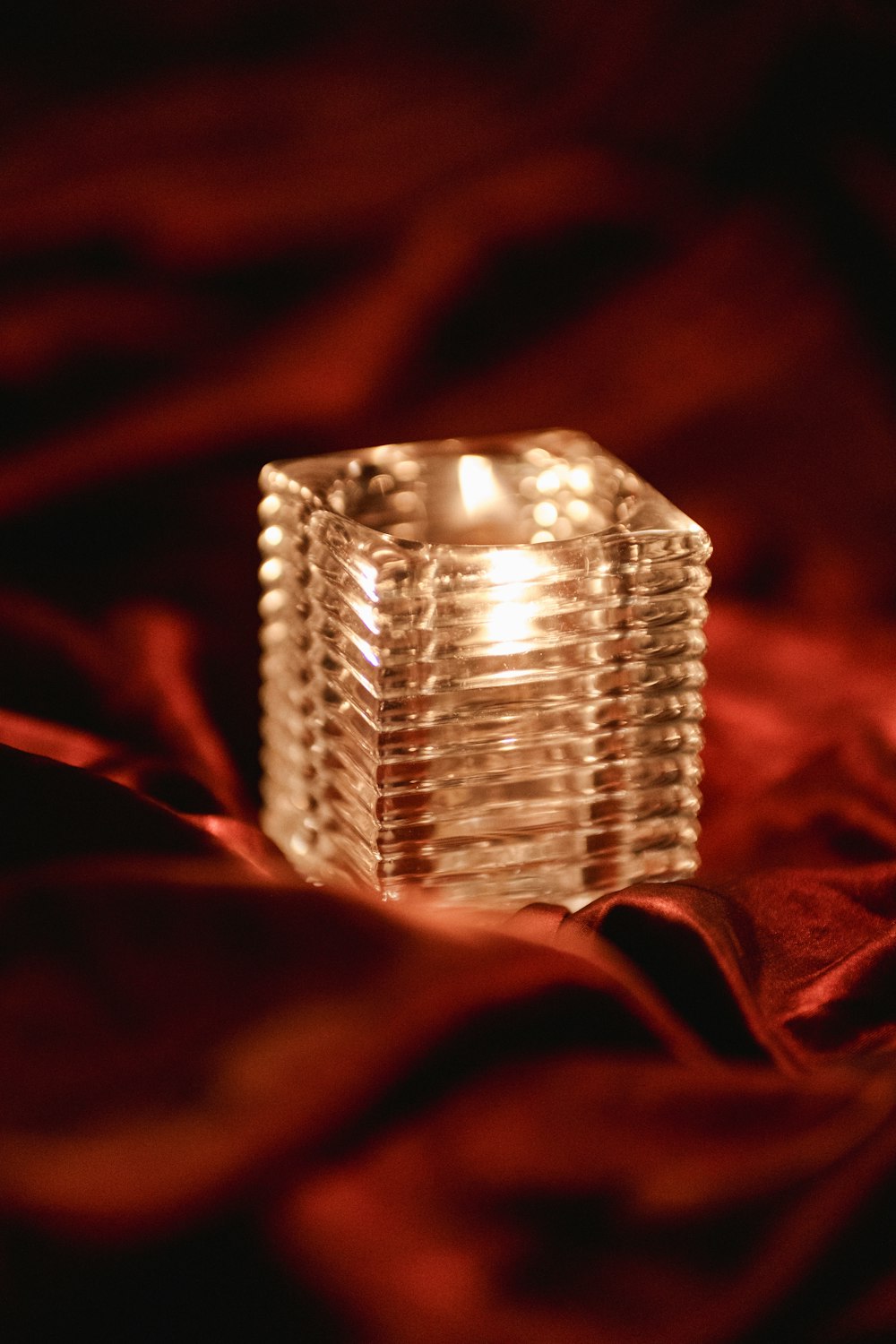 a lit candle sitting on top of a red blanket