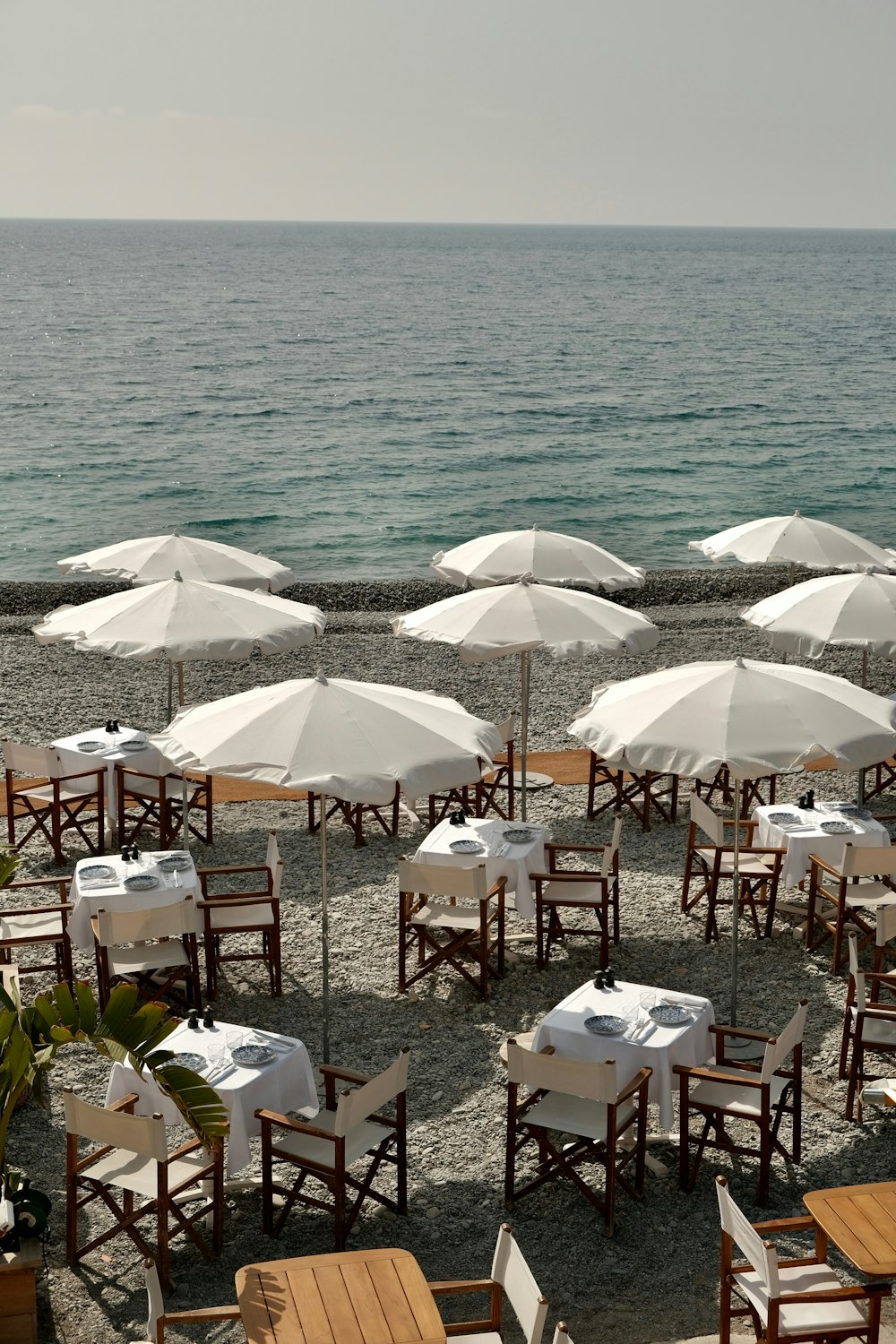 a bunch of tables and chairs with umbrellas on the beach
