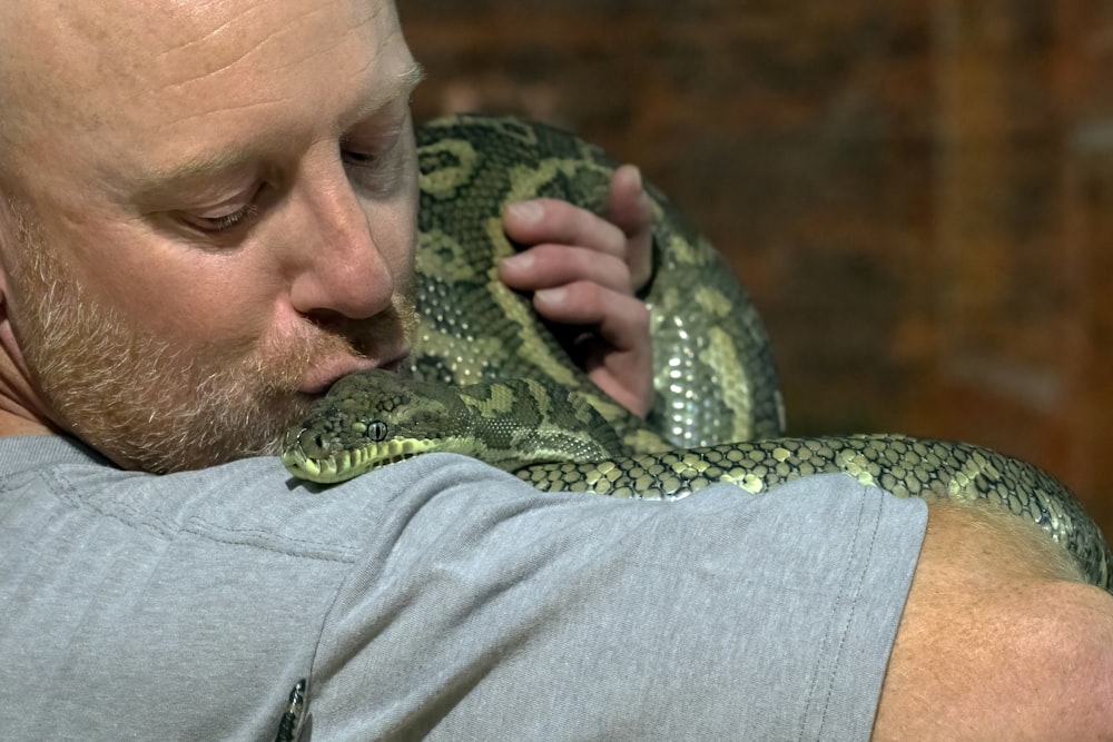 Un hombre sosteniendo una gran serpiente en sus brazos