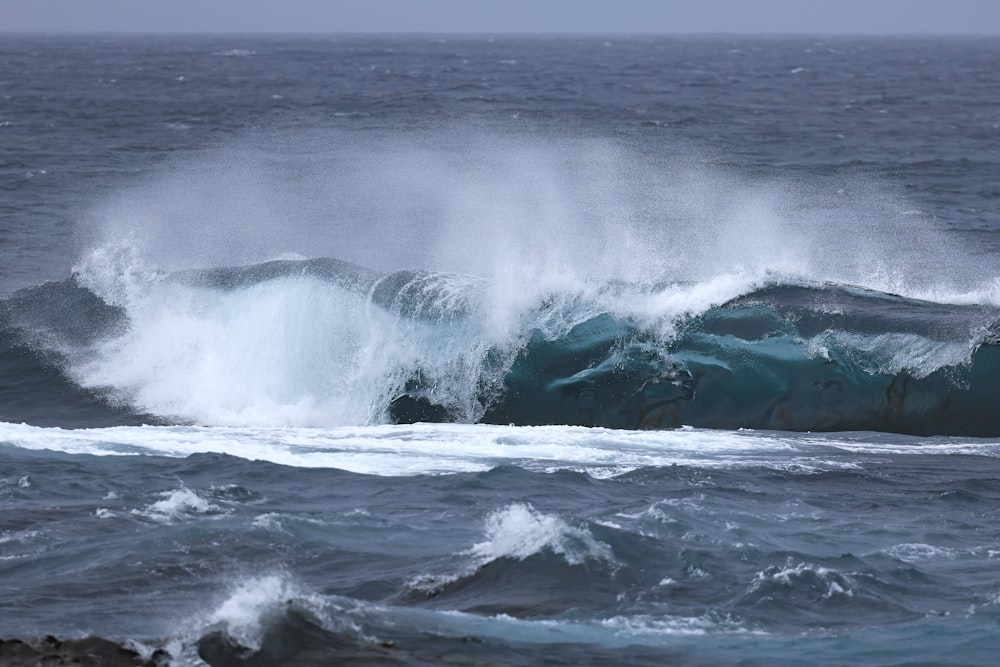 a large wave crashing into the shore of the ocean