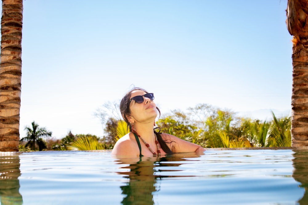 a woman in a pool with palm trees in the background