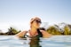a woman in a green bikini swims in a pool