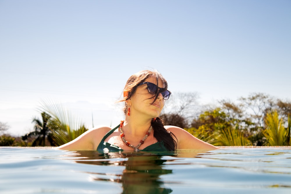 a woman in a green bikini swims in a pool