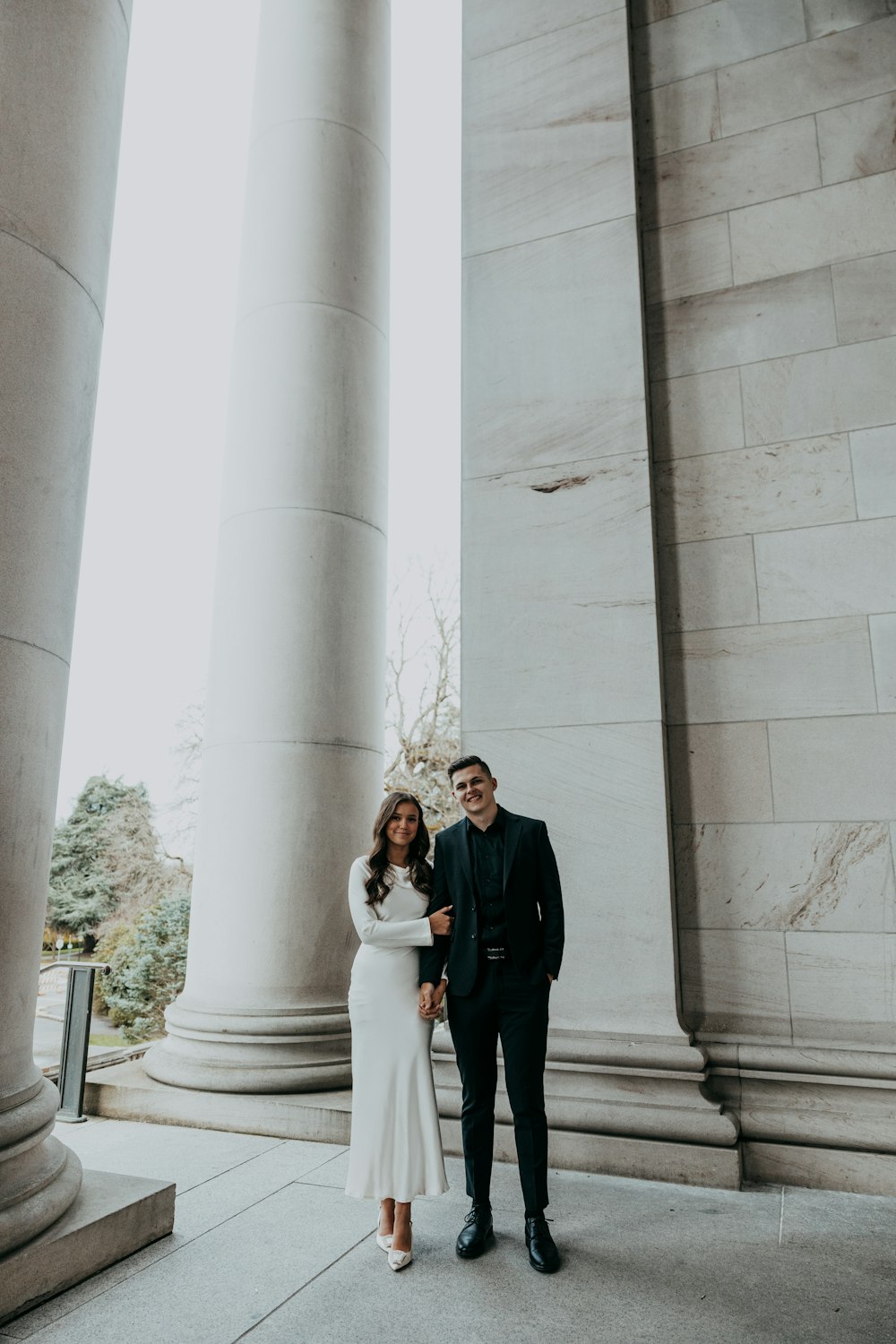 a man and a woman standing in front of pillars