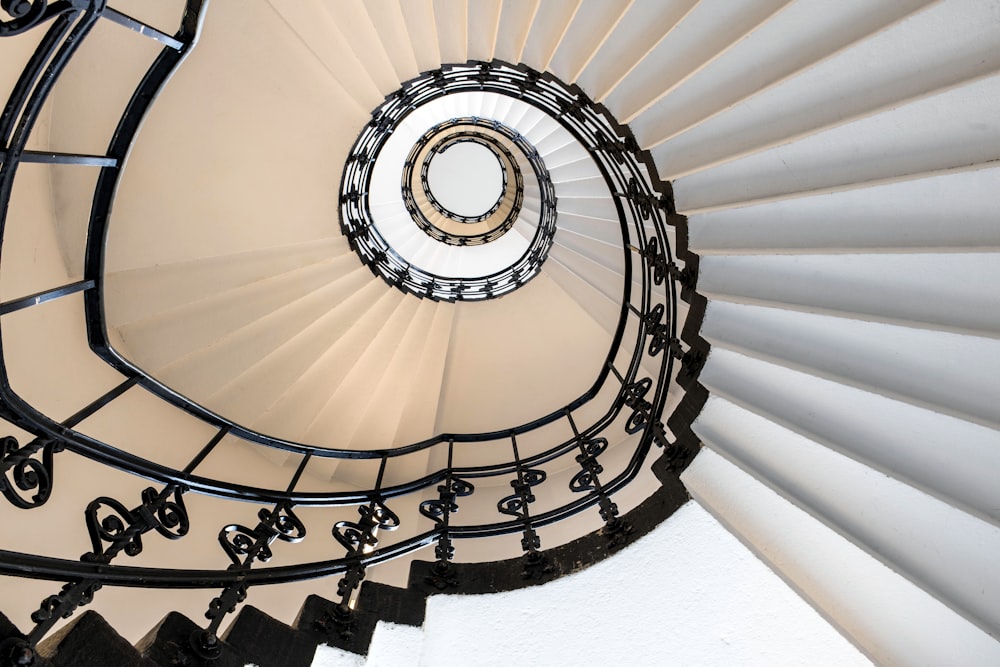 a spiral staircase with black railings and a white wall