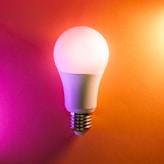 a white light bulb on an orange and pink background
