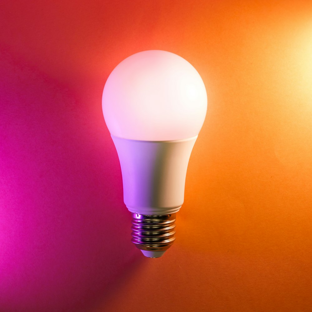 a white light bulb on an orange and pink background