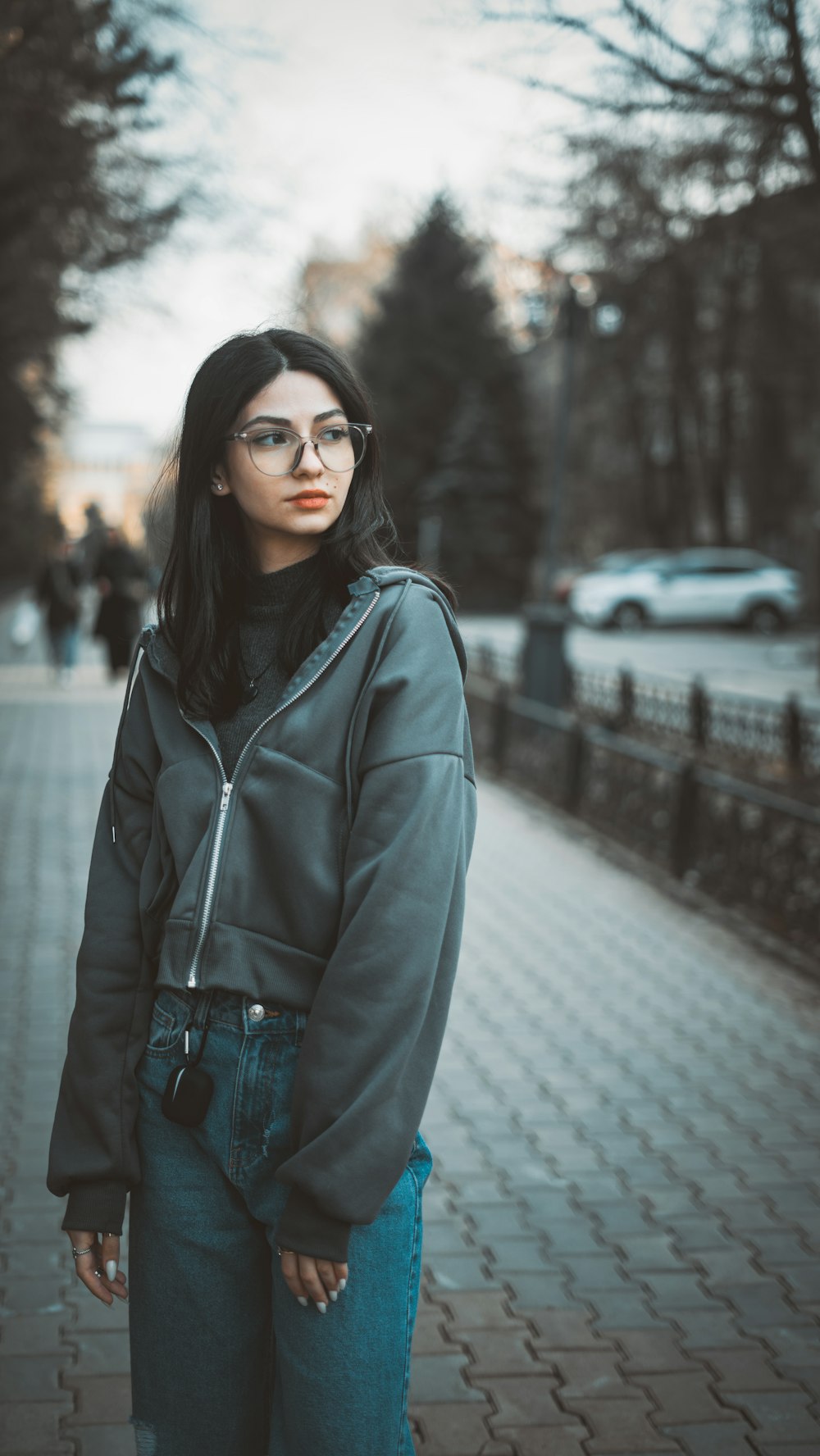 Une femme portant des lunettes debout sur un trottoir