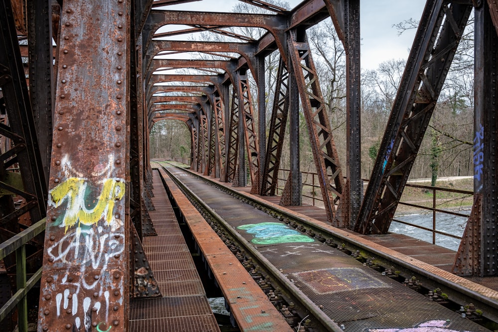 an old rusty bridge with graffiti on it