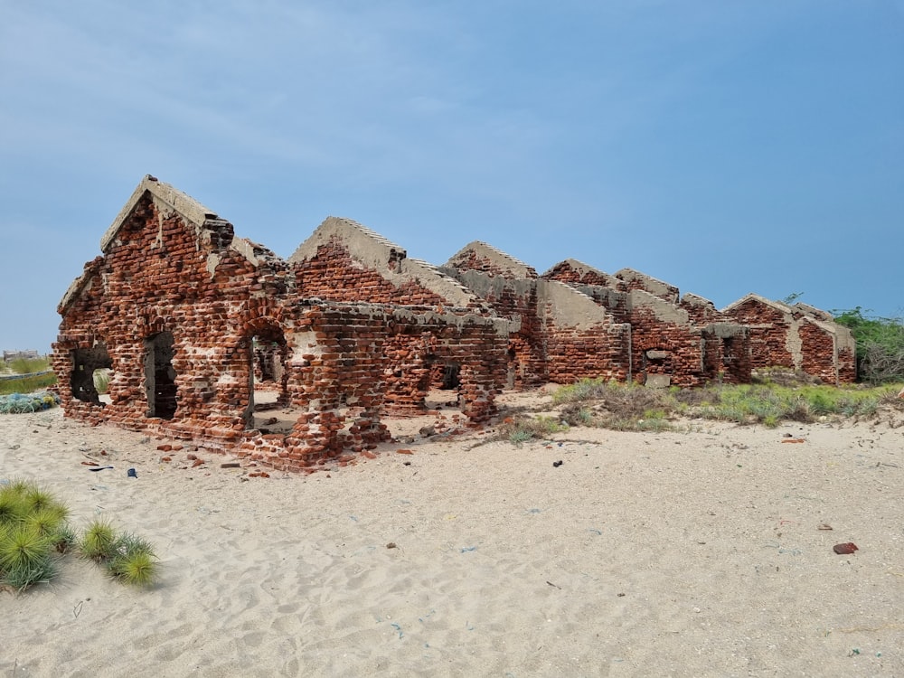 un vieux bâtiment en brique assis au sommet d’une plage de sable