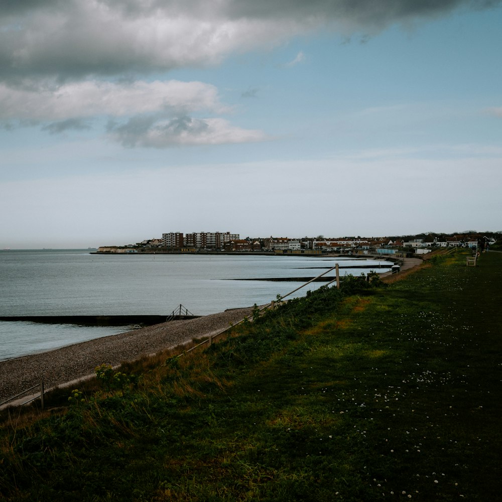 a large body of water sitting next to a lush green field