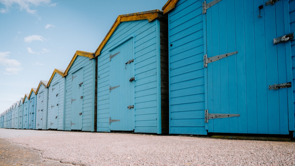 a row of blue beach huts sitting next to each other