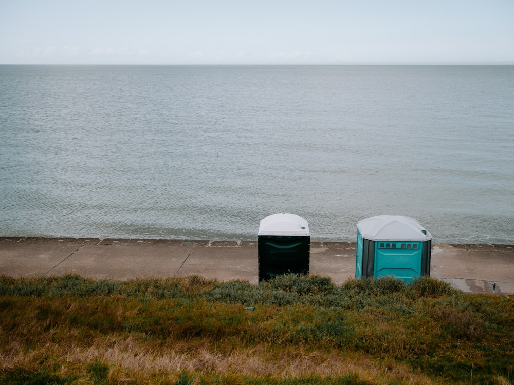 a couple of trash cans sitting next to a body of water