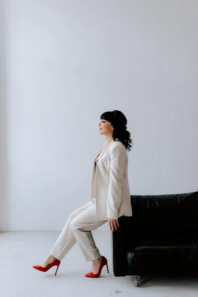 a woman sitting on a black couch in a white room