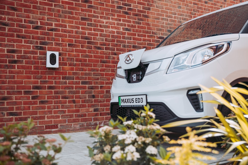 a white car parked in front of a brick wall