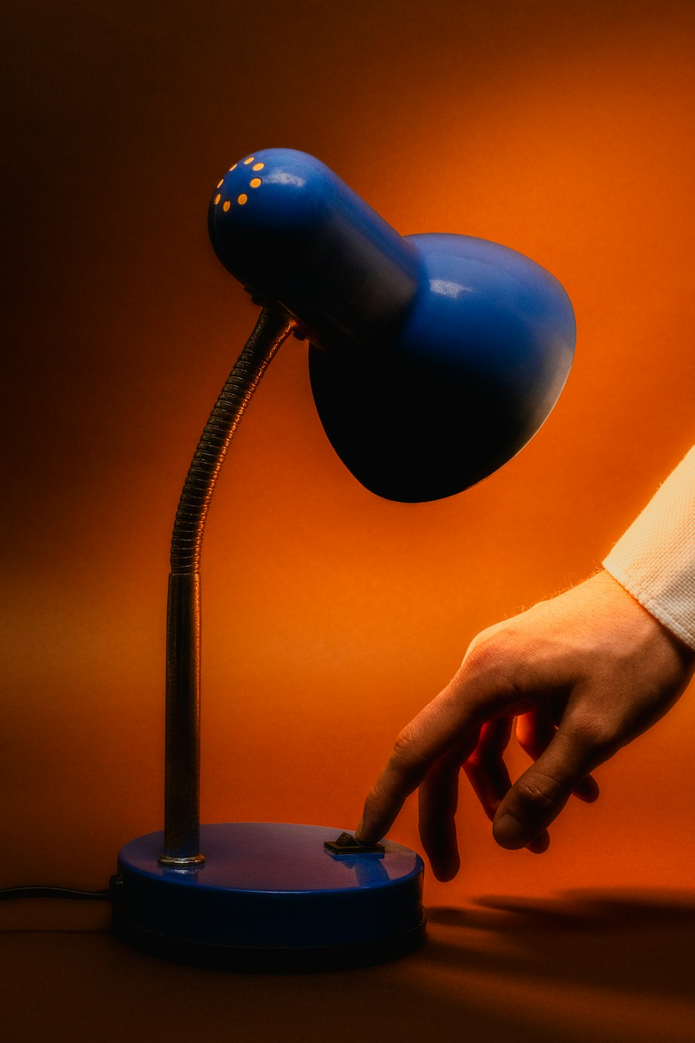 a hand is touching a blue lamp on a table