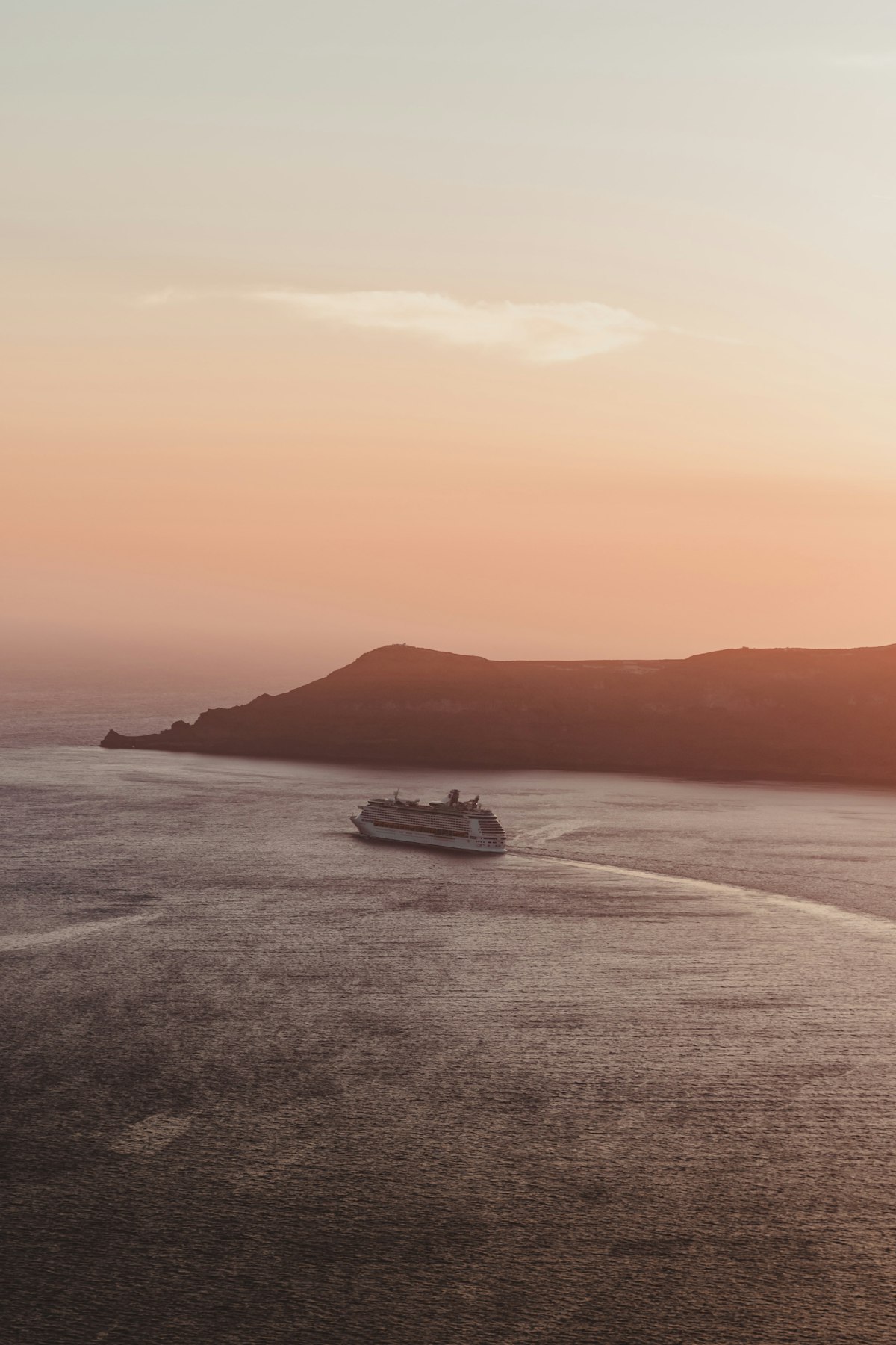 Nave da crociera che naviga nell&rsquo;oceano al tramonto con cielo arancione