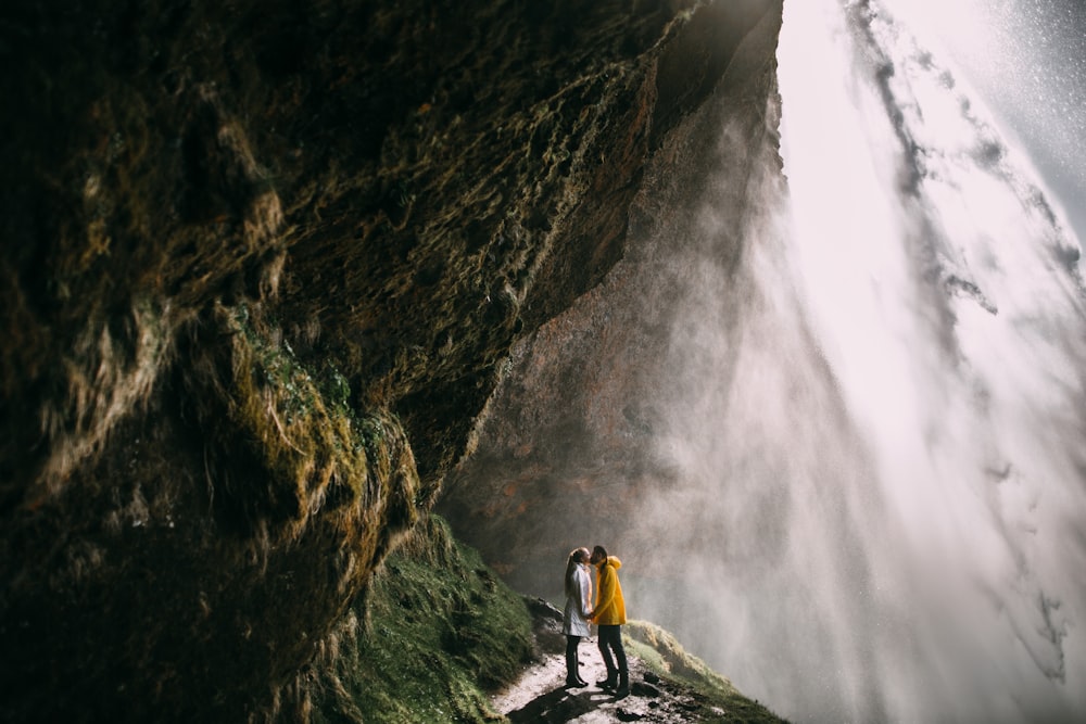 un homme et une femme debout devant une cascade