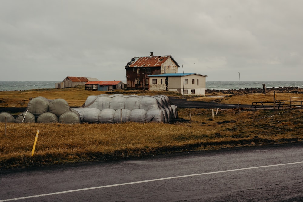 a house sitting on the side of a road next to a field