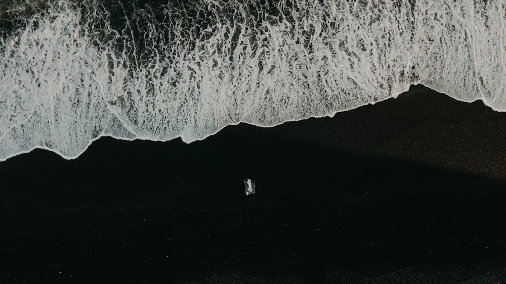 a couple of people standing on top of a beach next to the ocean