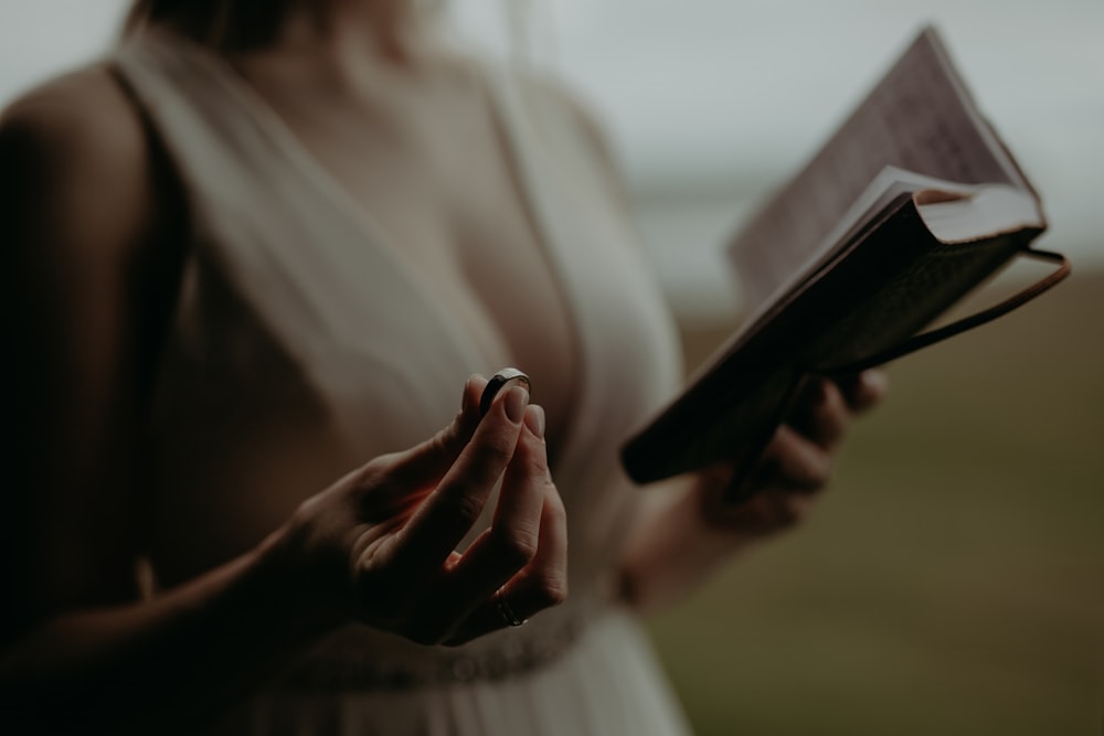 a woman in a white dress holding a book