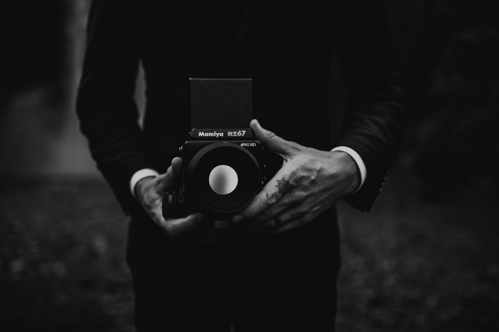 a black and white photo of a person holding a camera