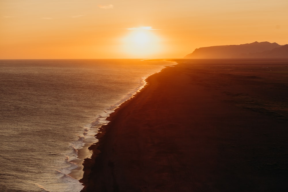 the sun is setting over the ocean on the beach