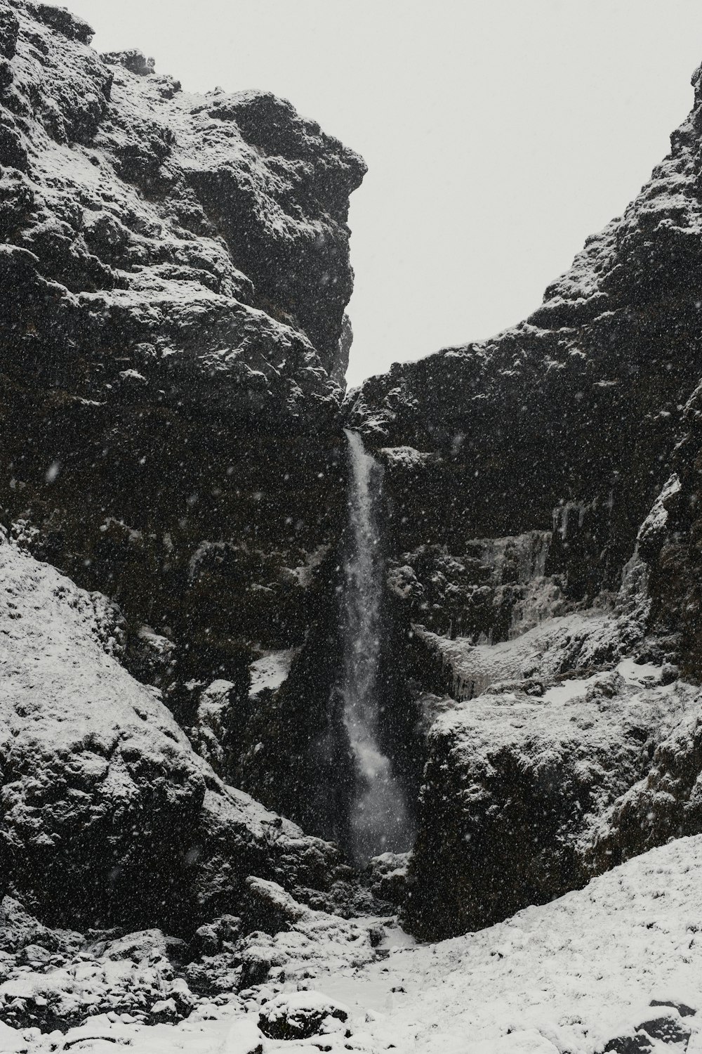 a man standing in front of a waterfall in the snow