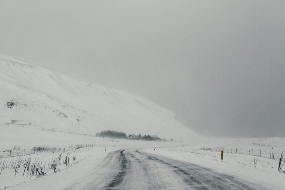 uma estrada coberta de neve com uma colina ao fundo