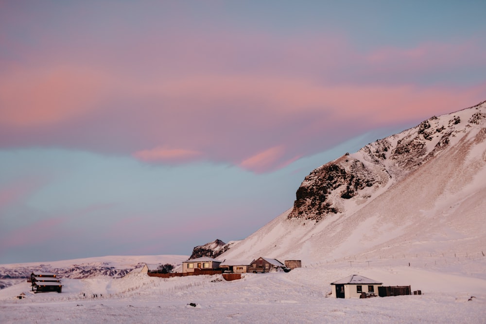 uma montanha coberta de neve com uma casa em primeiro plano
