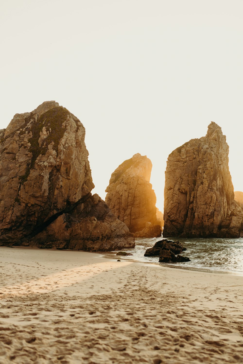 Un par de grandes rocas sentadas en la parte superior de una playa de arena