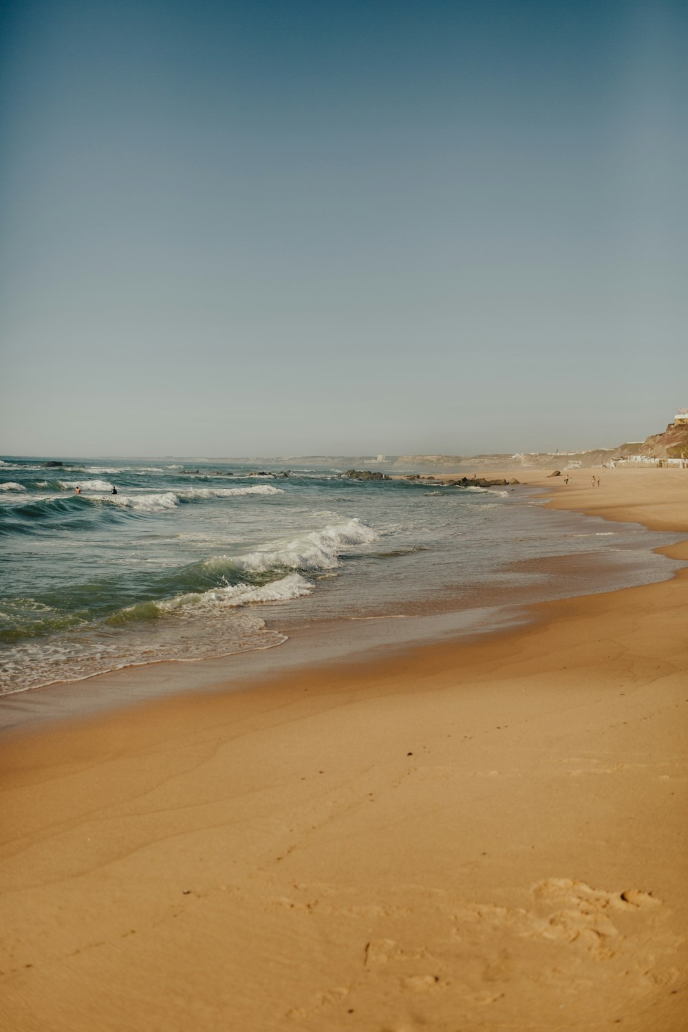 a sandy beach with waves coming in to shore