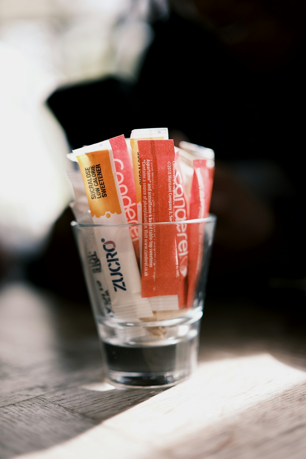 a glass filled with candy sticks on top of a wooden table