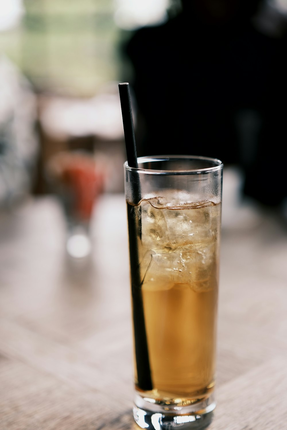 a glass of ice tea with a black straw
