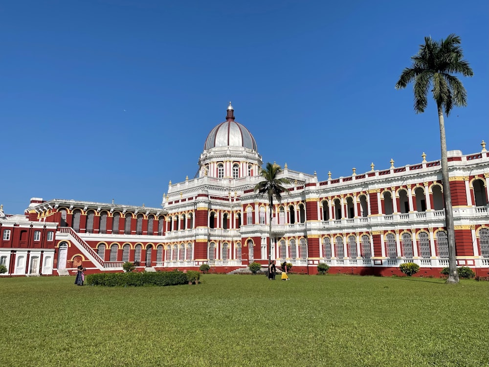 a large white and red building with a palm tree in front of it