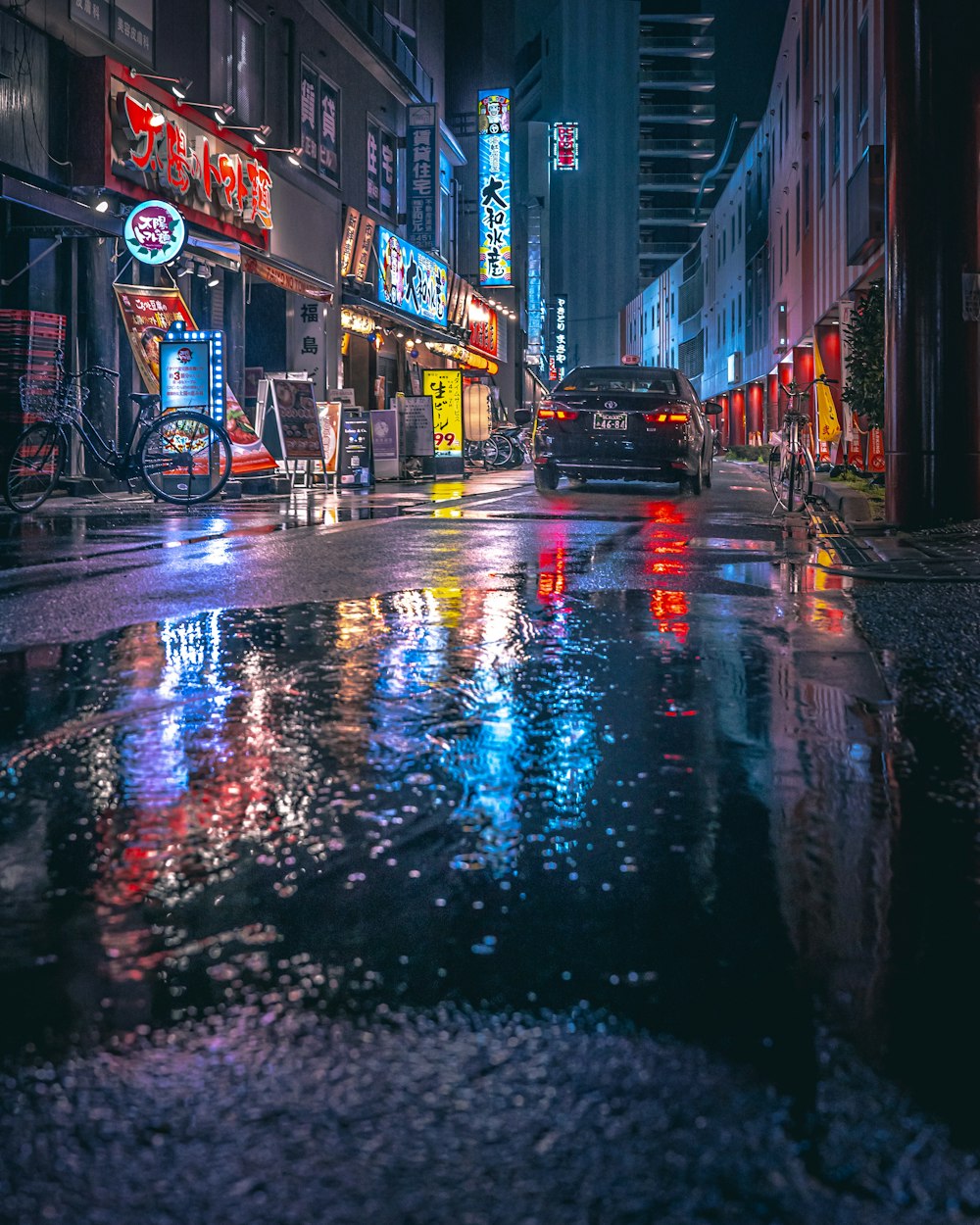 a city street at night with a puddle of water