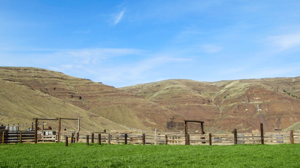 a fenced in field with mountains in the background